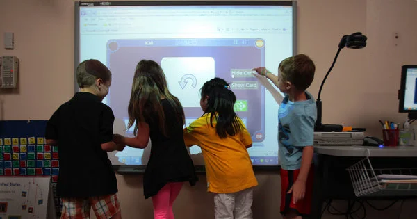 Four children learning together at an interactive screen